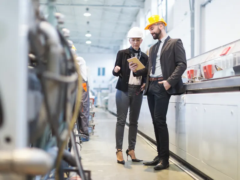 Deux gestionnaires en casque de sécurité dans une usine